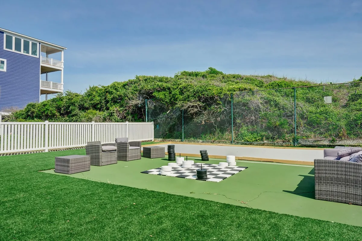 An inviting outdoor space with a large chess set, comfortable seating, and lush greenery in the background. The area encourages socializing, relaxation, and playful outdoor activities, all set within a peaceful, resort-like environment.