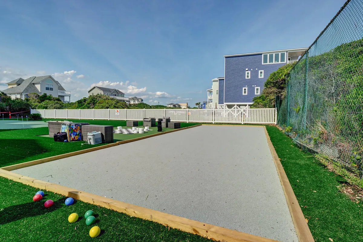 A sunny, welcoming bocce ball court surrounded by greenery and a nearby seating area, ideal for groups to host casual games, socialize, and enjoy the outdoors together.